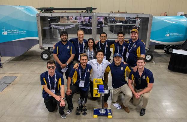 The 2022 Cal Maritime CWC Team, with turbine and foundation, in front of the DOE wind tunnel. Front row (left to right): Jake Nelson (ME ‘23), Jacob Piña, (ME ‘22), Kenny Shin (ME ’22), Andrew Cavinta (GSMA ‘22), Will Tucker (GSMA ‘22). Back row (left to right): Sid Kumar (ME ‘23), Tom Nordenholz (Faculty Advisor), Jackie Garcia (FET ‘22), Quinton Cacal (FET ‘22), Ryan Martinez (IBL ‘22), Ryan Storz (Faculty Advisor). Other team members who couldn’t attend: Aaron Breitinger (ME ‘22), Miles Krauter (ME ‘23), William Laurent (ME ‘22), Matthew Rizzi (IBL ‘24).