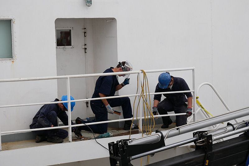 Three cadets chipping paint