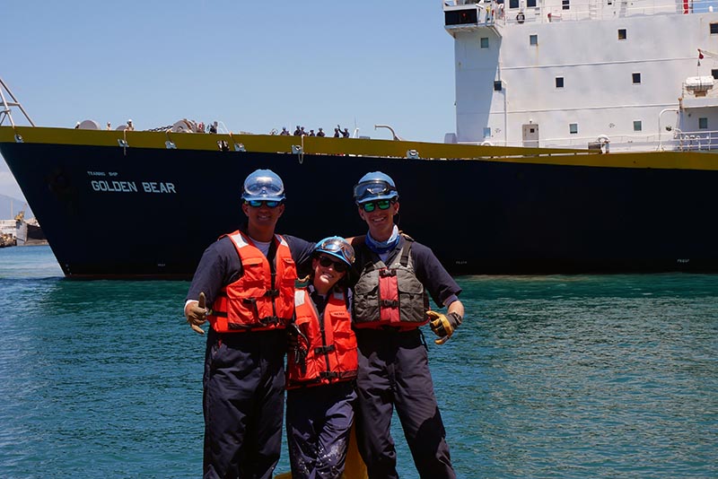 Three cadets on shore with TSGB in background