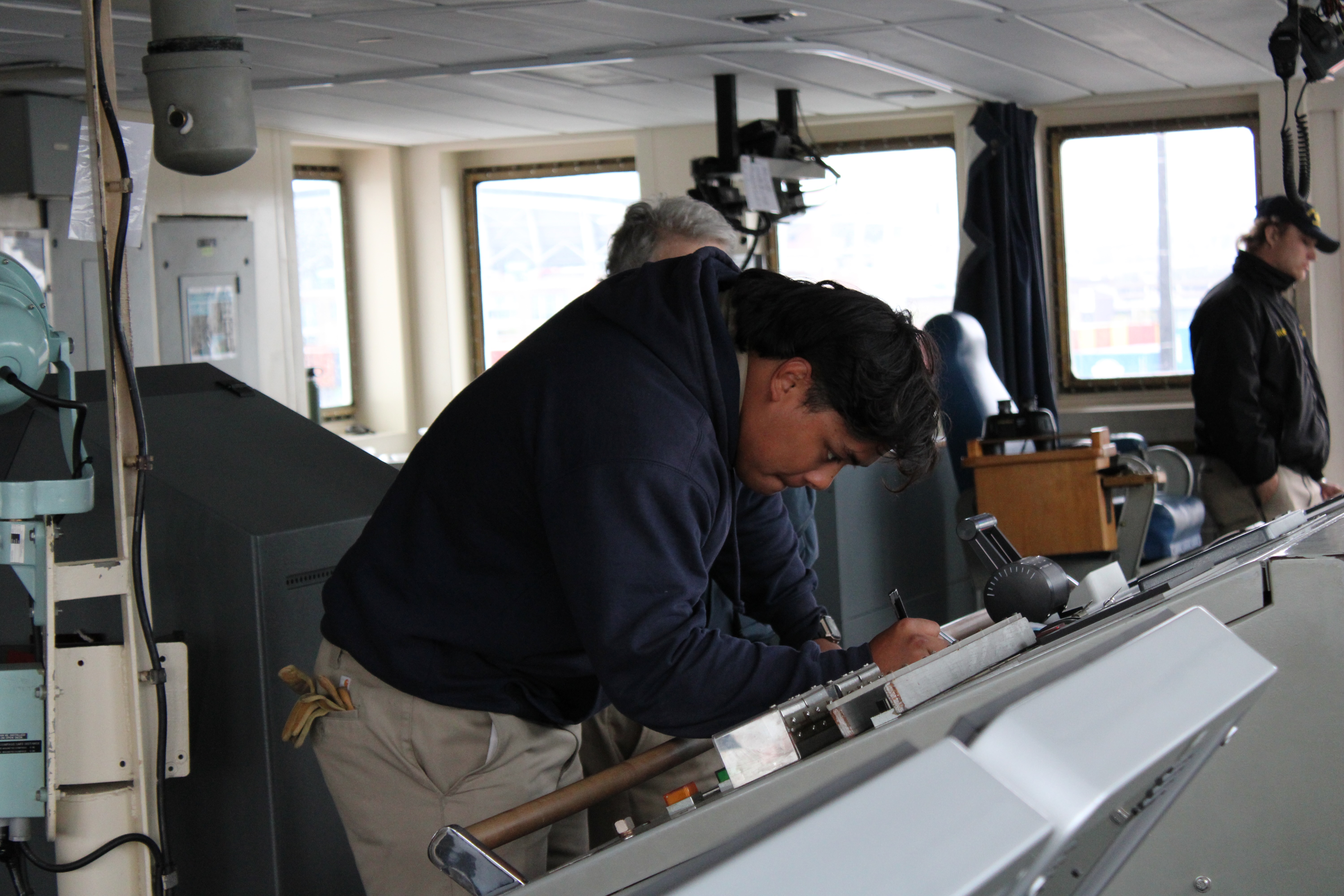 Cadet 3rd Mate Solomon Kaupu at the Engine Order Telegraph, and keeping the Bell Book